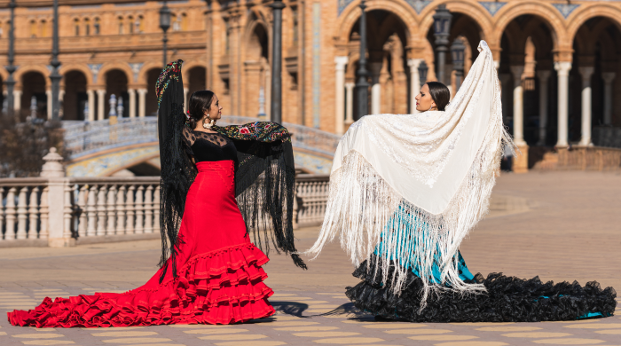 Dos flamencas bailando con vestido de flamenca y mantón